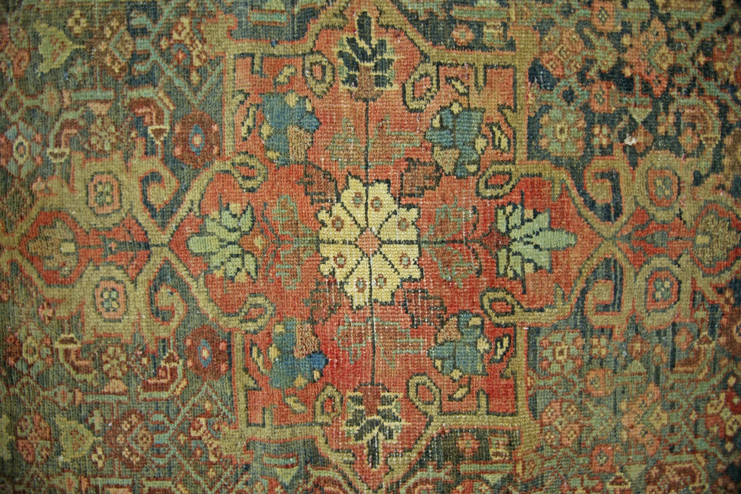 A vintage handmade Persian rug featuring a central floral medallion on a rust-colored field.