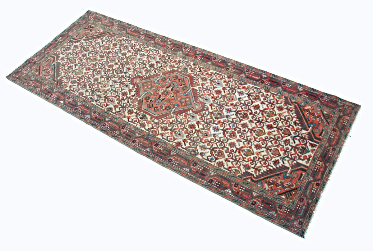 Vintage Persian Hossainabad runner featuring geometric medallions and angular floral motifs in red, blue, and cream tones.
