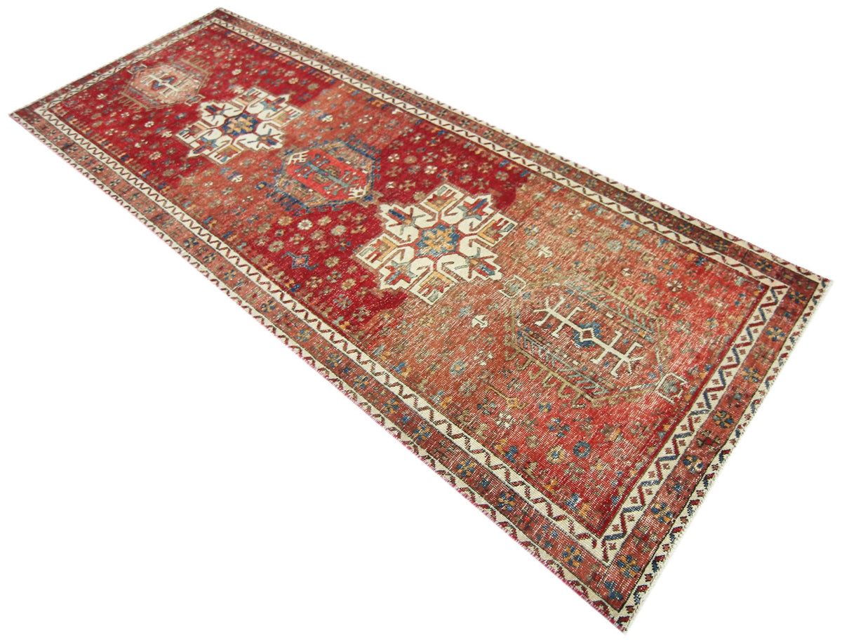 Hand-knotted Persian Karaja runner featuring geometric medallions in red, blue, and ivory on a wool pile.