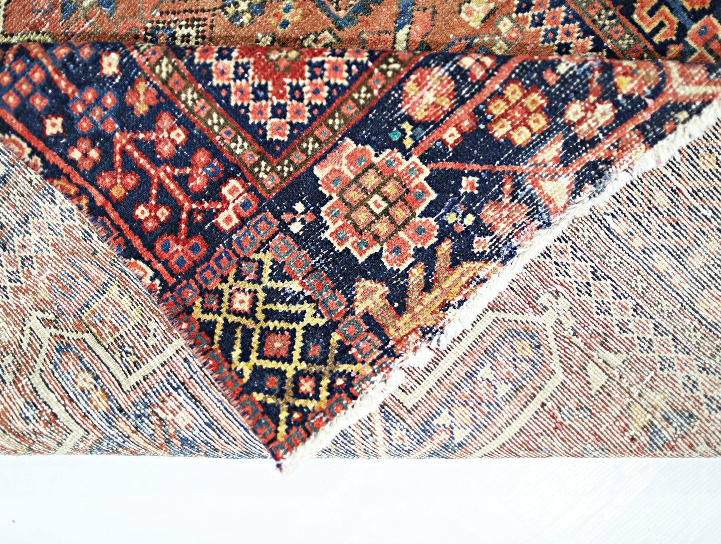 A vintage Persian Karaja runner featuring intricate geometric patterns in red, blue, and cream.