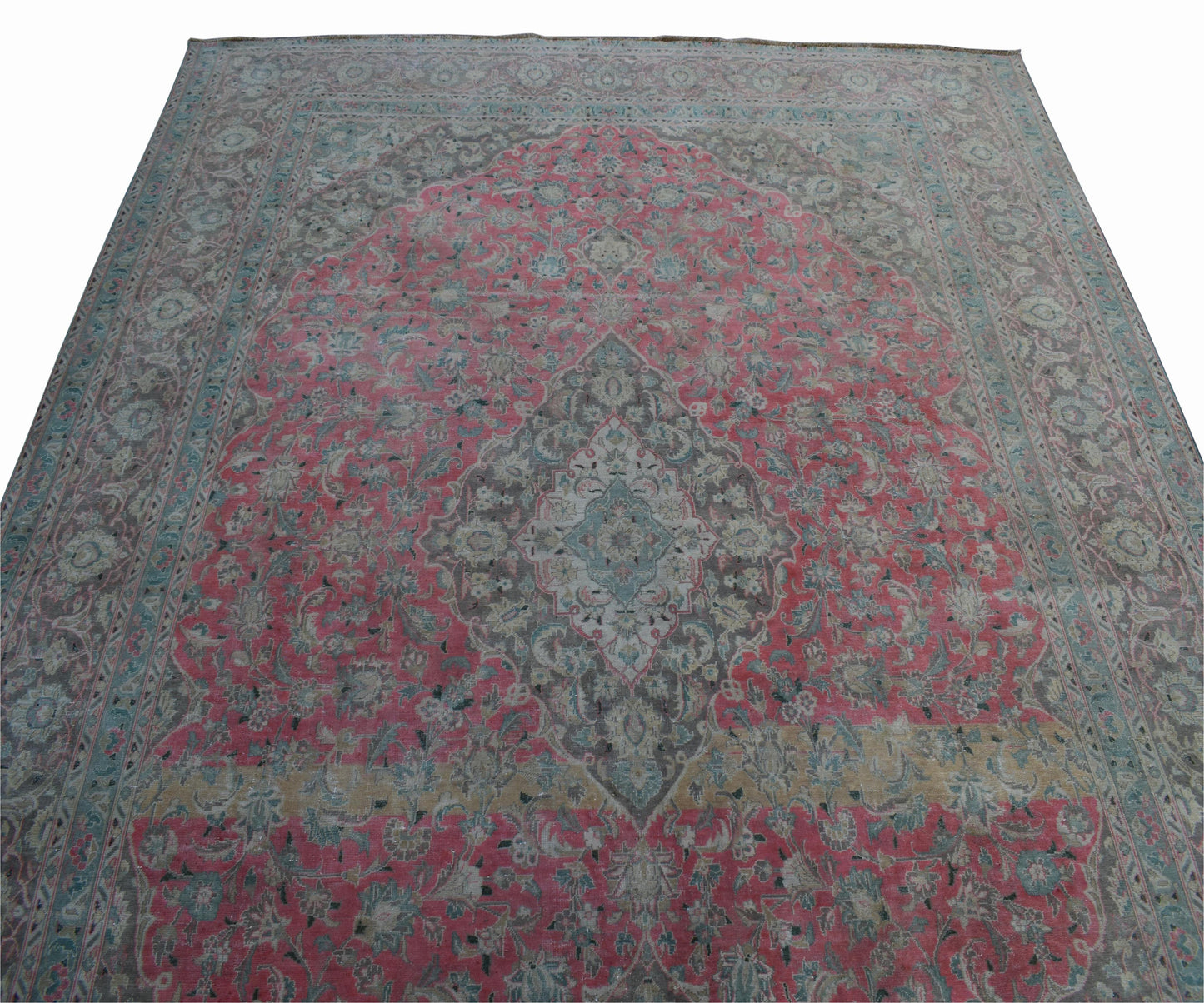 A vintage handwoven Persian Kashan rug featuring a central floral medallion on a pink field.