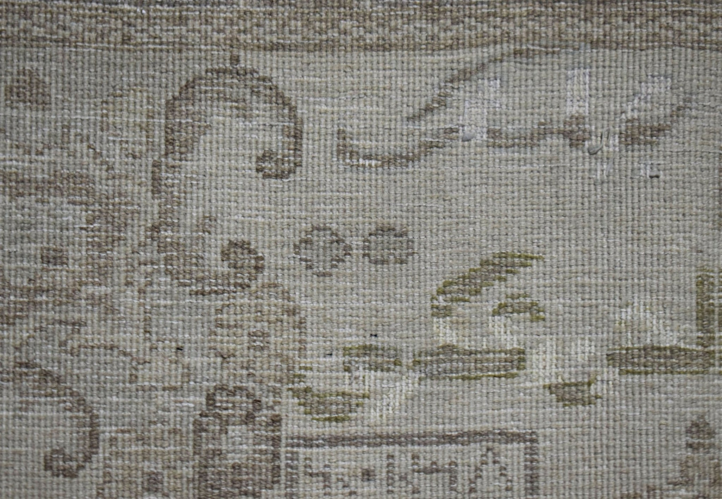 A close-up view of a vintage Persian Kerman rug featuring intricate, faded floral patterns.