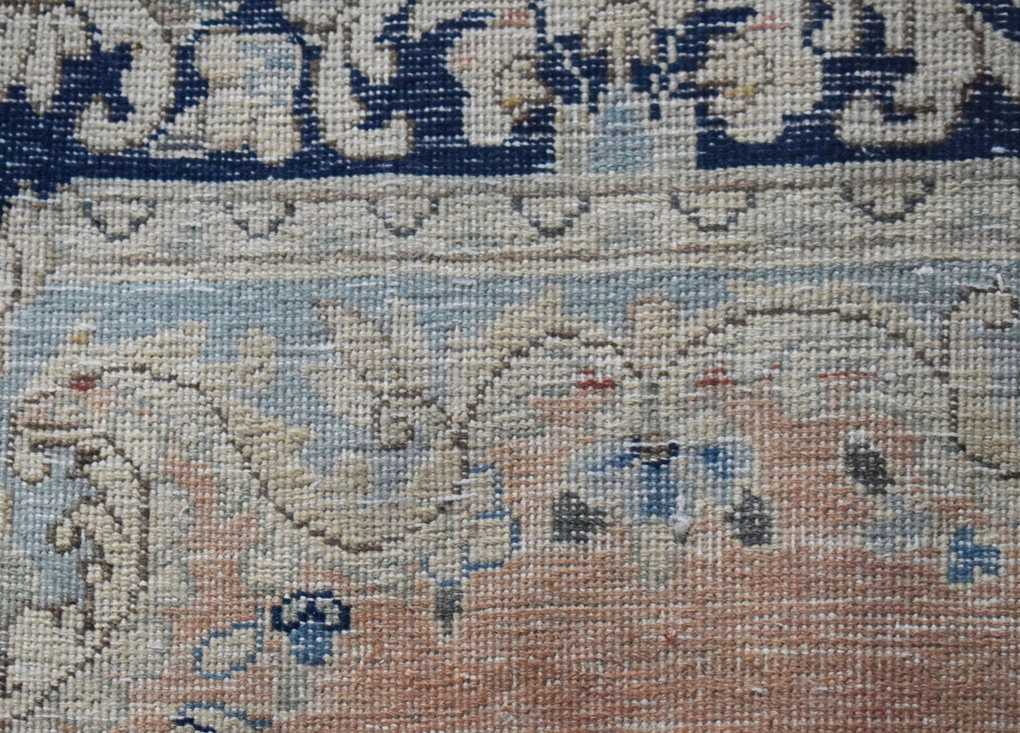 A close-up view of a vintage Persian Kerman rug featuring intricate floral patterns in soft tones.