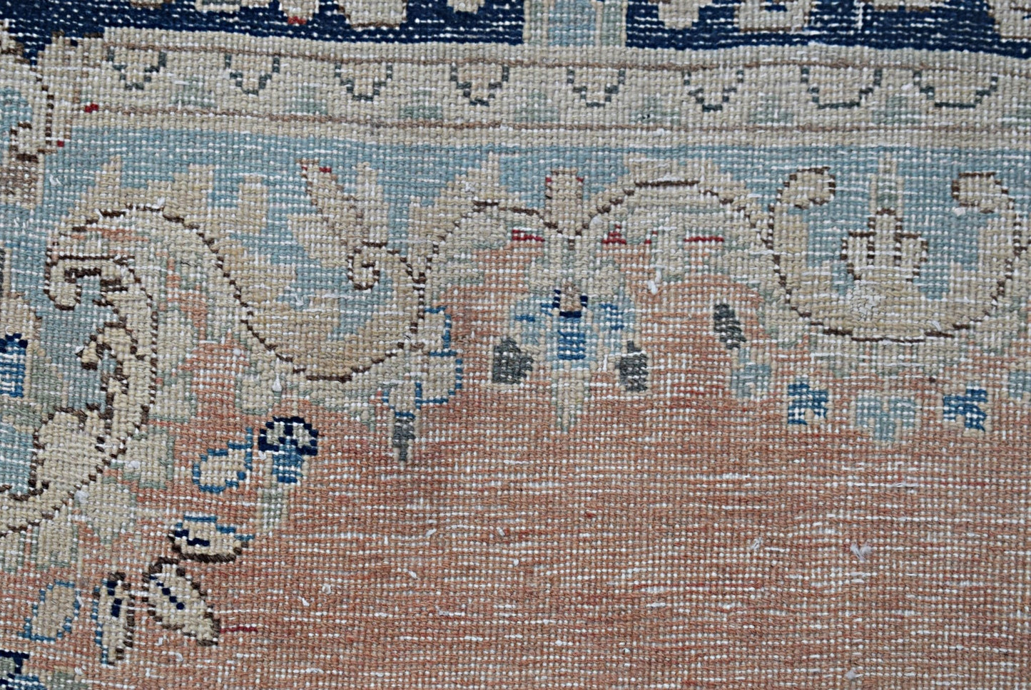 A close-up of a vintage Persian Kerman rug featuring intricate floral patterns in soft tones.
