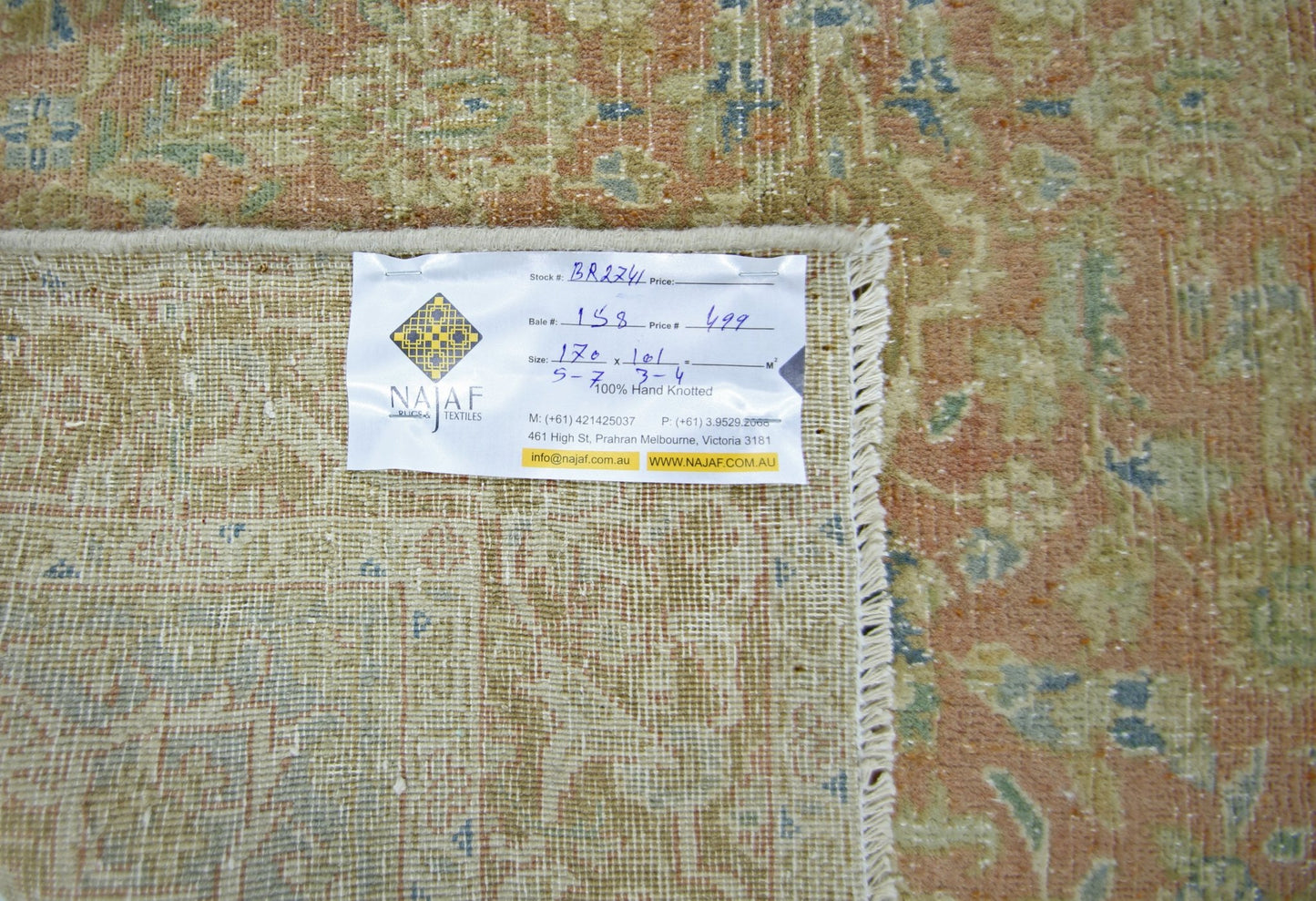 A vintage Persian rug with a faded floral pattern in shades of orange, green, and blue.
