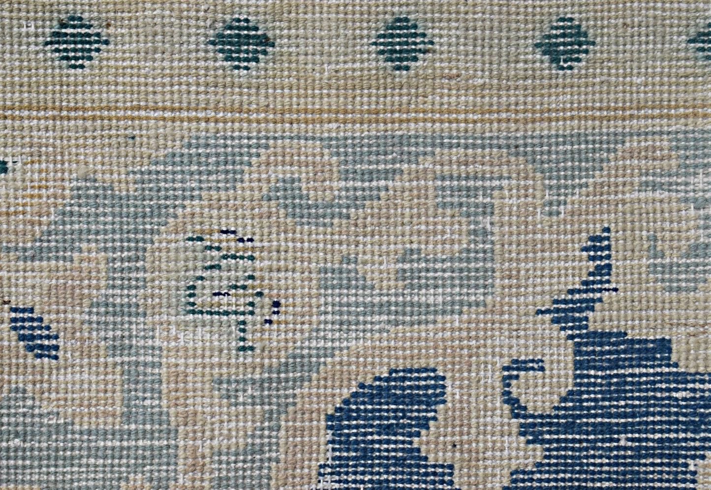 A close-up of a vintage Persian Kerman rug featuring intricate blue floral patterns on a beige base.