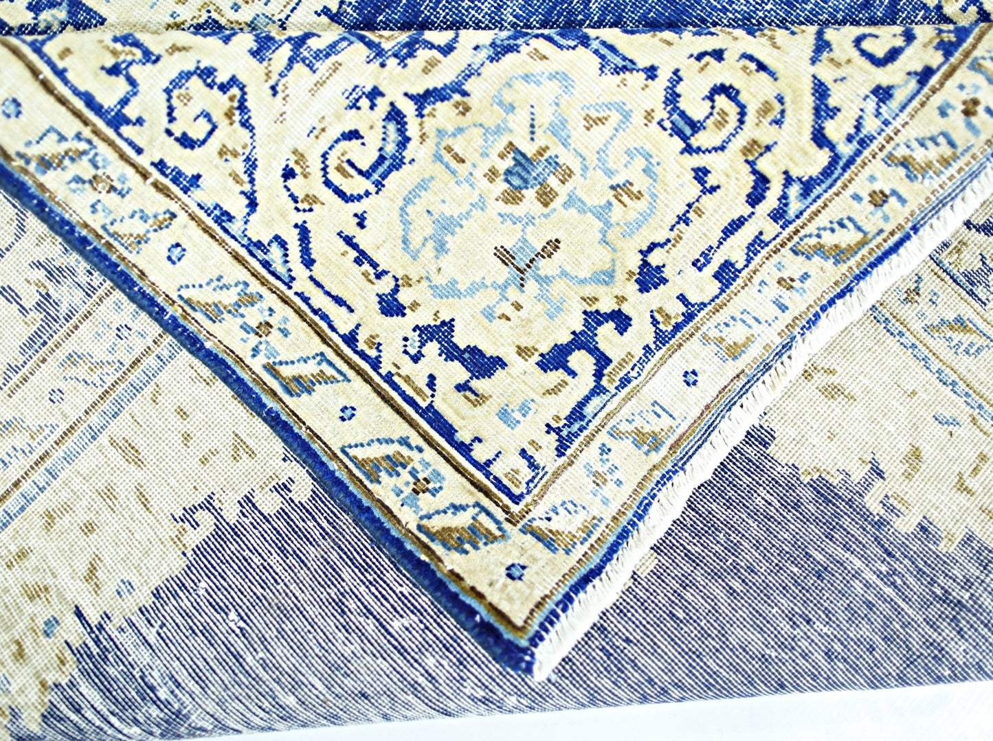 A folded vintage Persian Kerman rug featuring an intricate blue and cream floral medallion design.