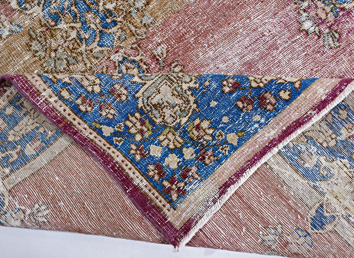 A vintage Persian Kerman rug featuring a floral medallion pattern in blue, pink, and tan tones.