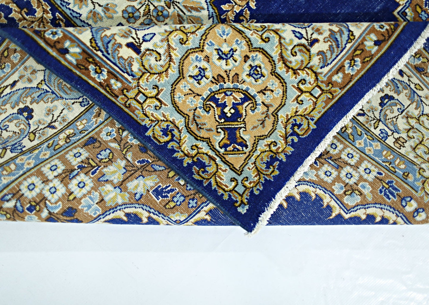 A vintage Persian Kerman rug featuring a blue and tan floral medallion pattern.
