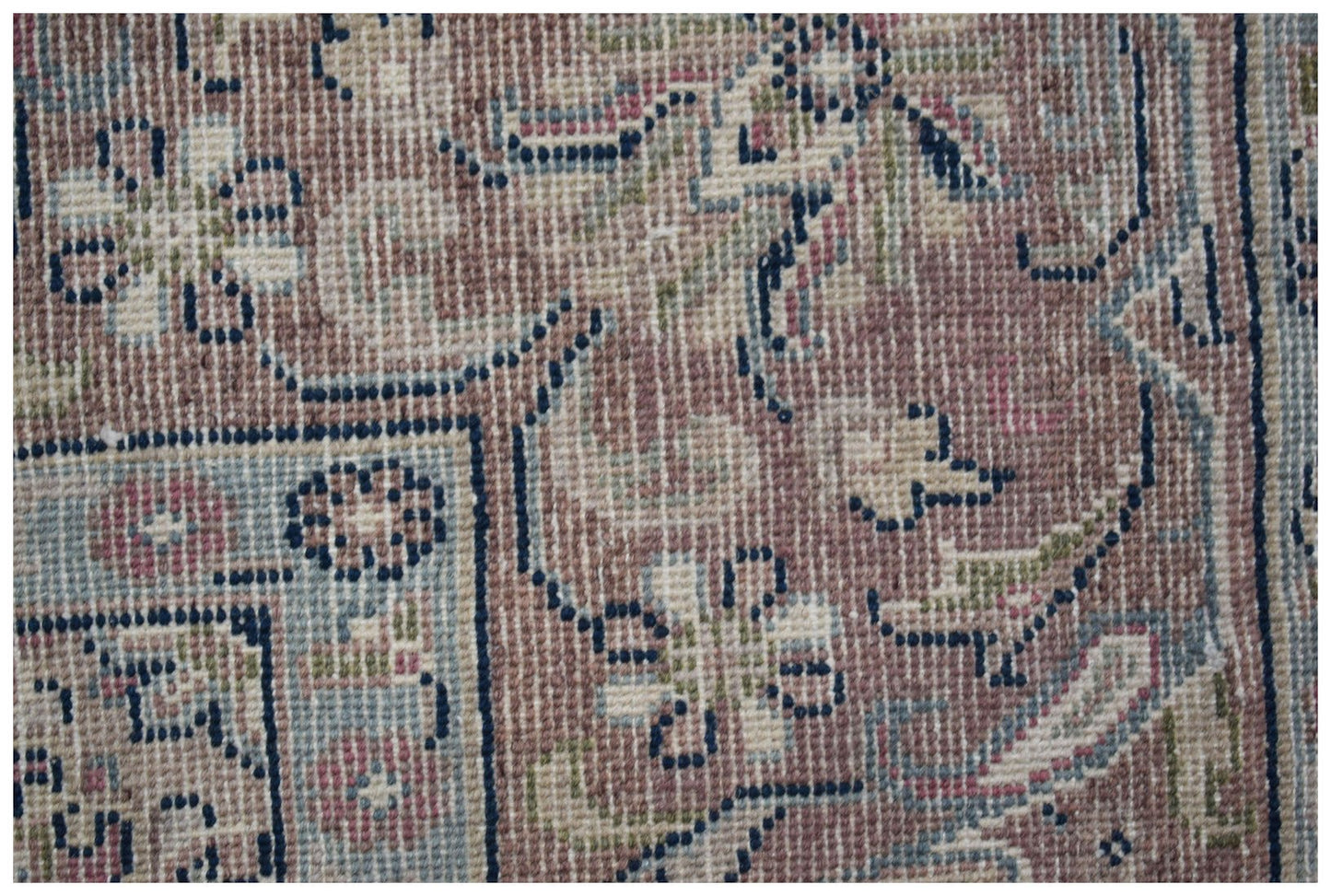 A close-up of a vintage Persian Kerman rug featuring intricate floral patterns in muted tones.