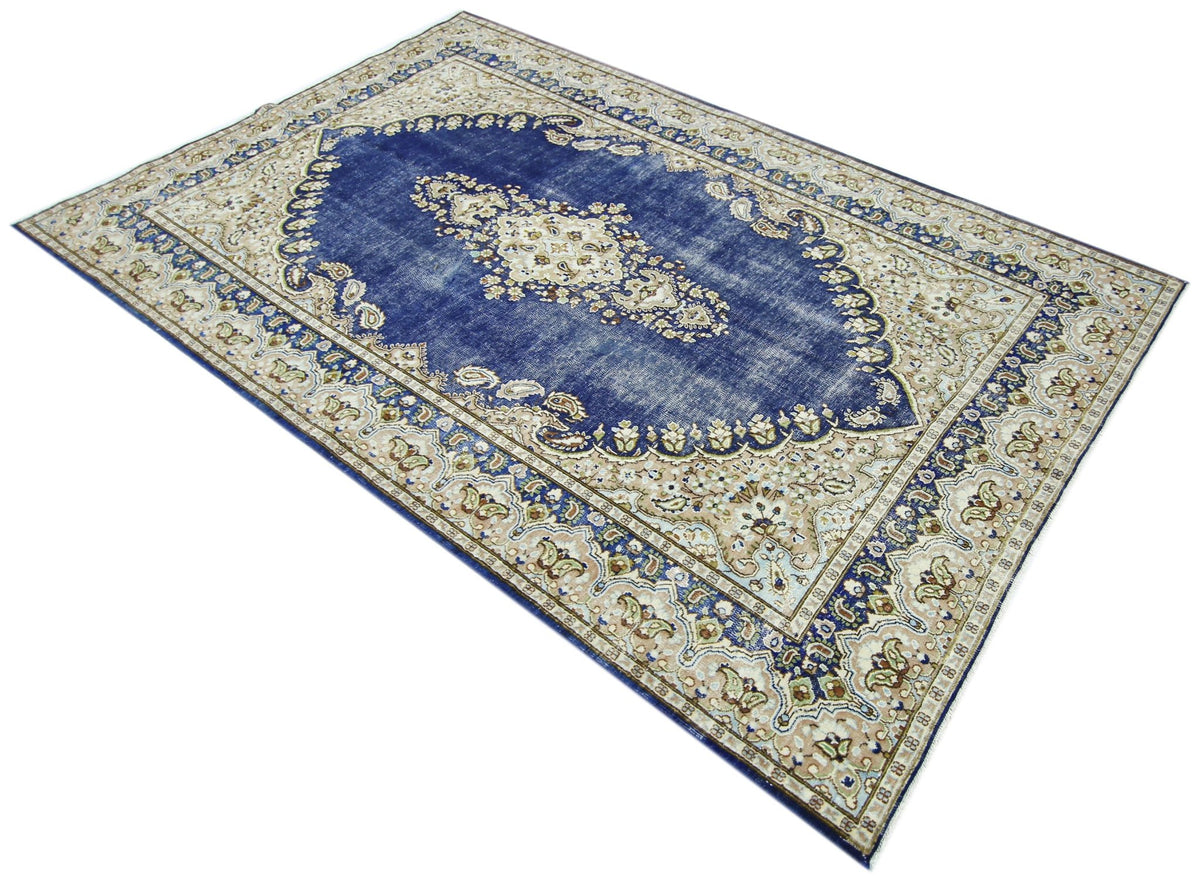 Vintage Persian Kerman wool rug featuring a deep blue central medallion and intricate floral cream borders.