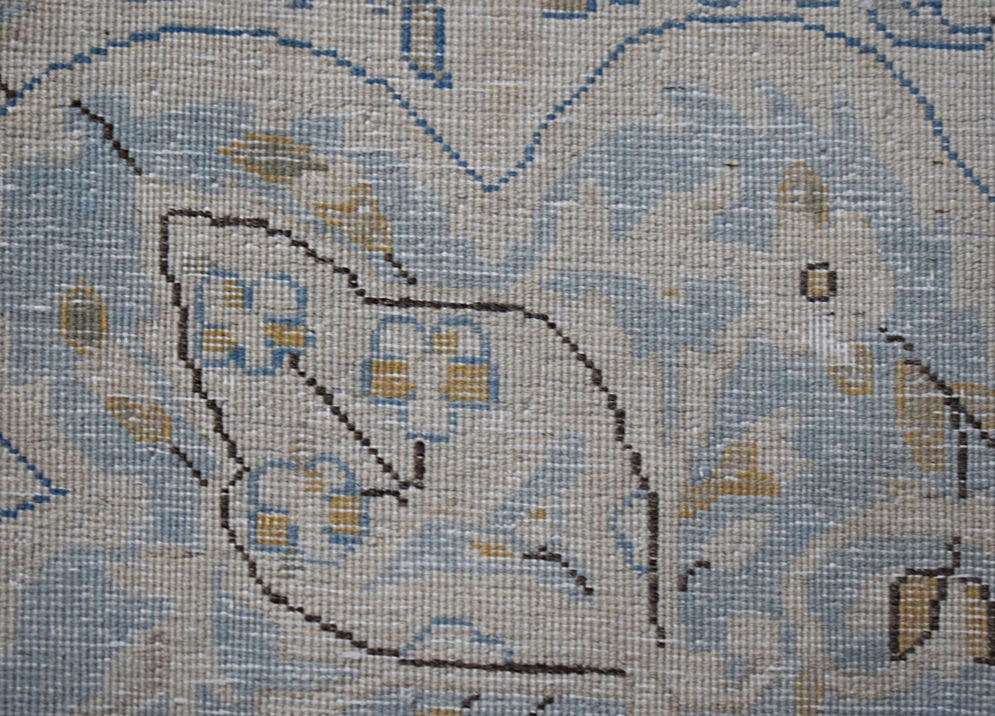A close-up of a vintage Persian Kerman rug featuring intricate floral patterns in soft blue tones.