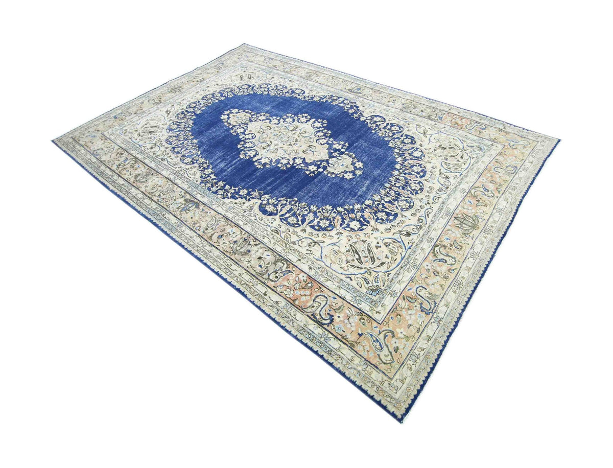 Vintage Persian Kerman rug featuring a central blue medallion with intricate floral patterns on a cream and peach field.