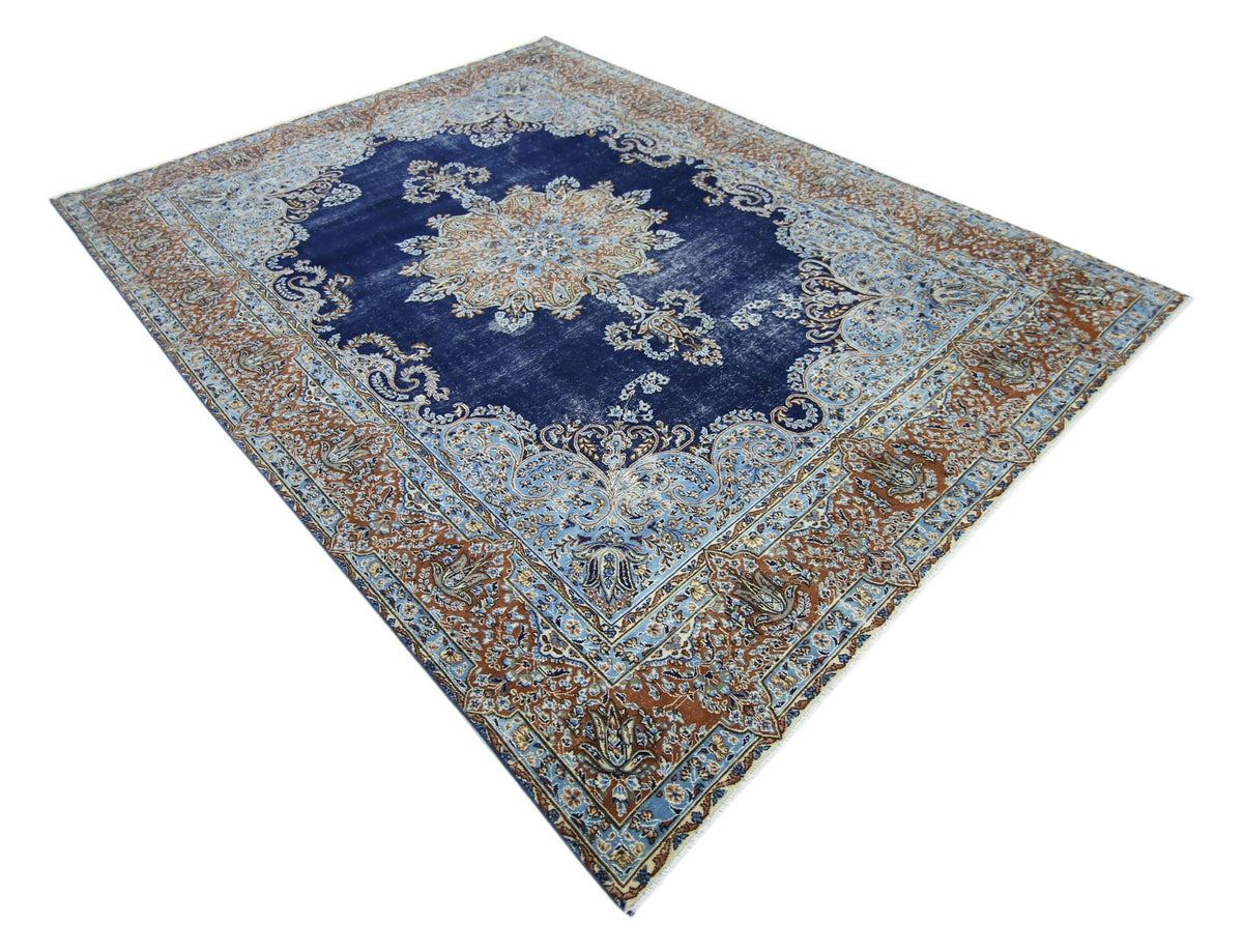 Vintage Persian Kerman wool rug with a deep blue central medallion and intricate floral patterns in rust and light blue.