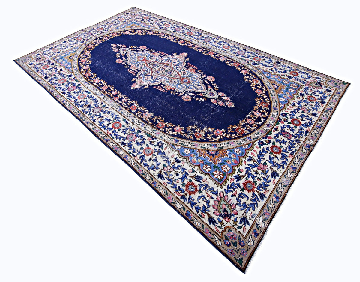 Vintage Persian Kerman rug featuring a deep blue central medallion and intricate floral borders in wool on cotton.