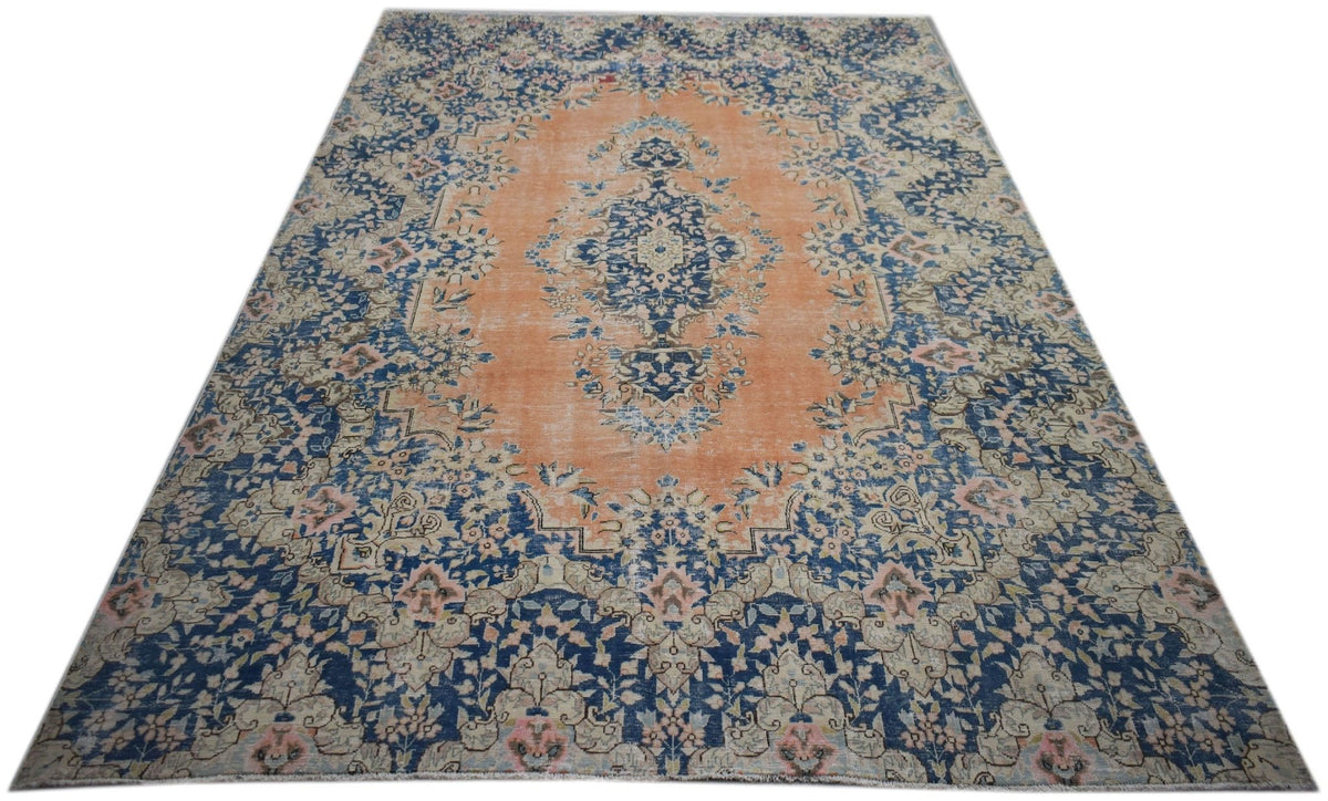 Vintage Persian Kerman rug featuring an intricate blue floral pattern and central medallion on a soft orange field.