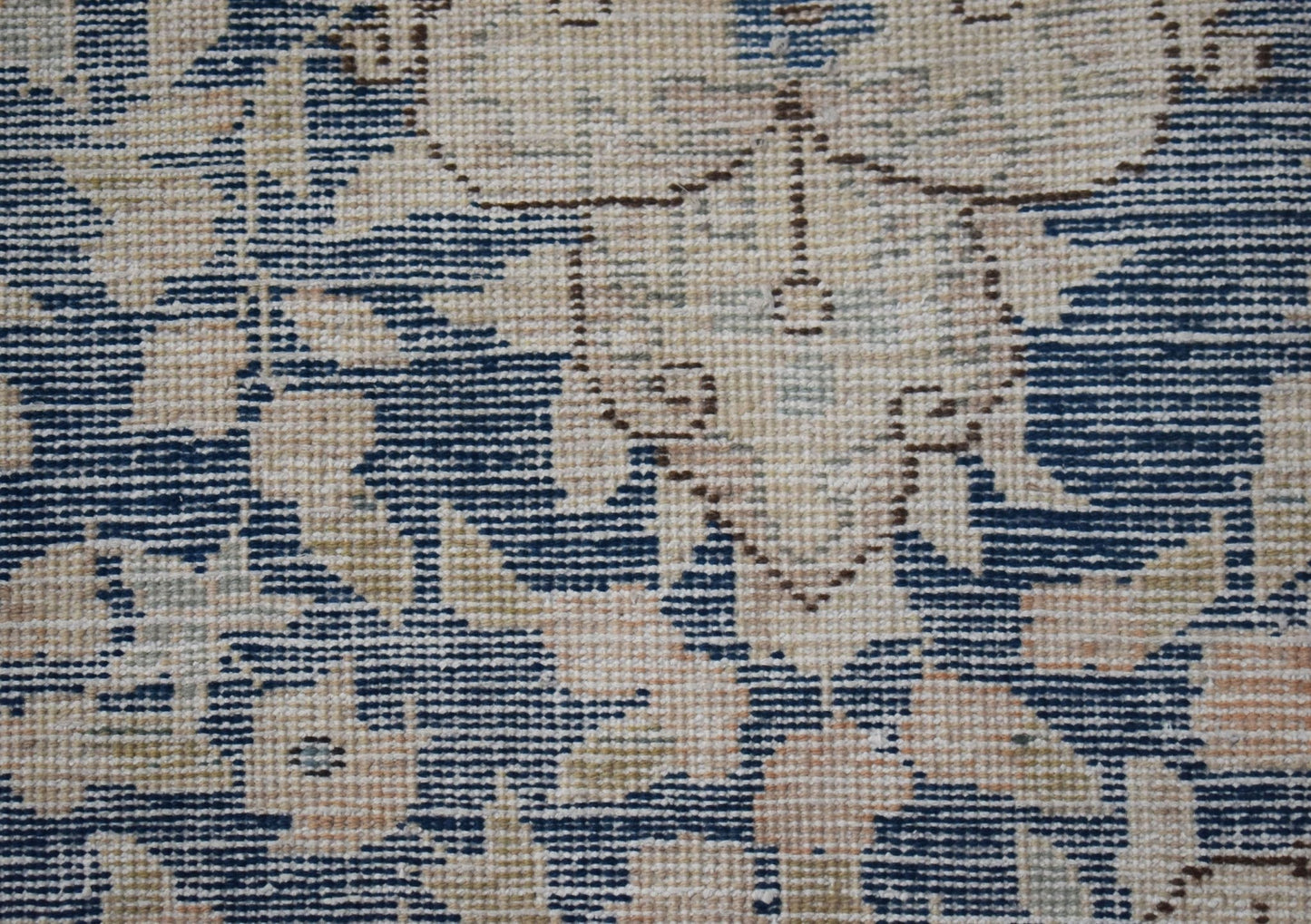 A close-up of a vintage Persian Kerman rug featuring intricate floral patterns in blue and cream.