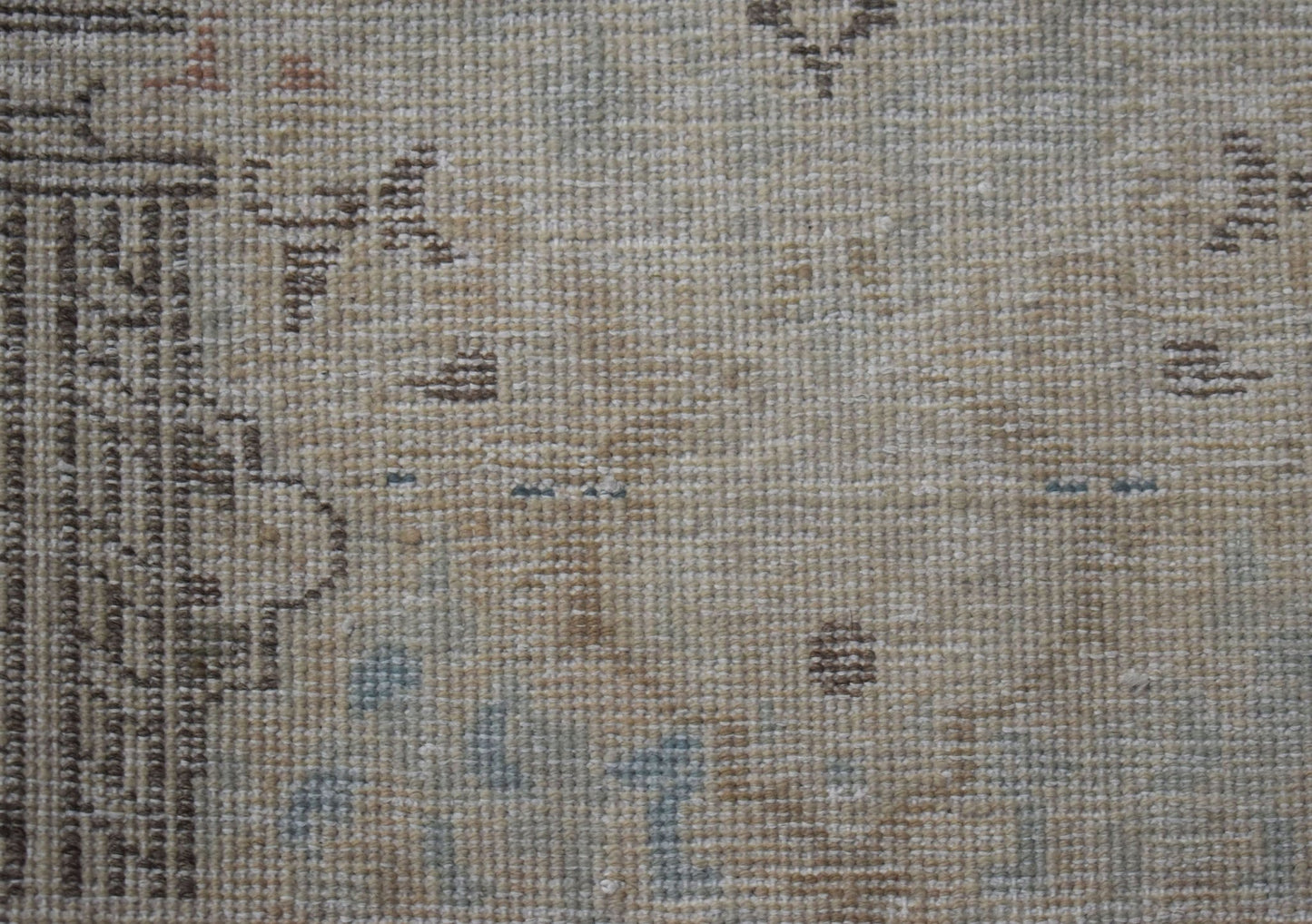 A close-up view of a vintage Persian Kerman rug featuring intricate, faded floral patterns.