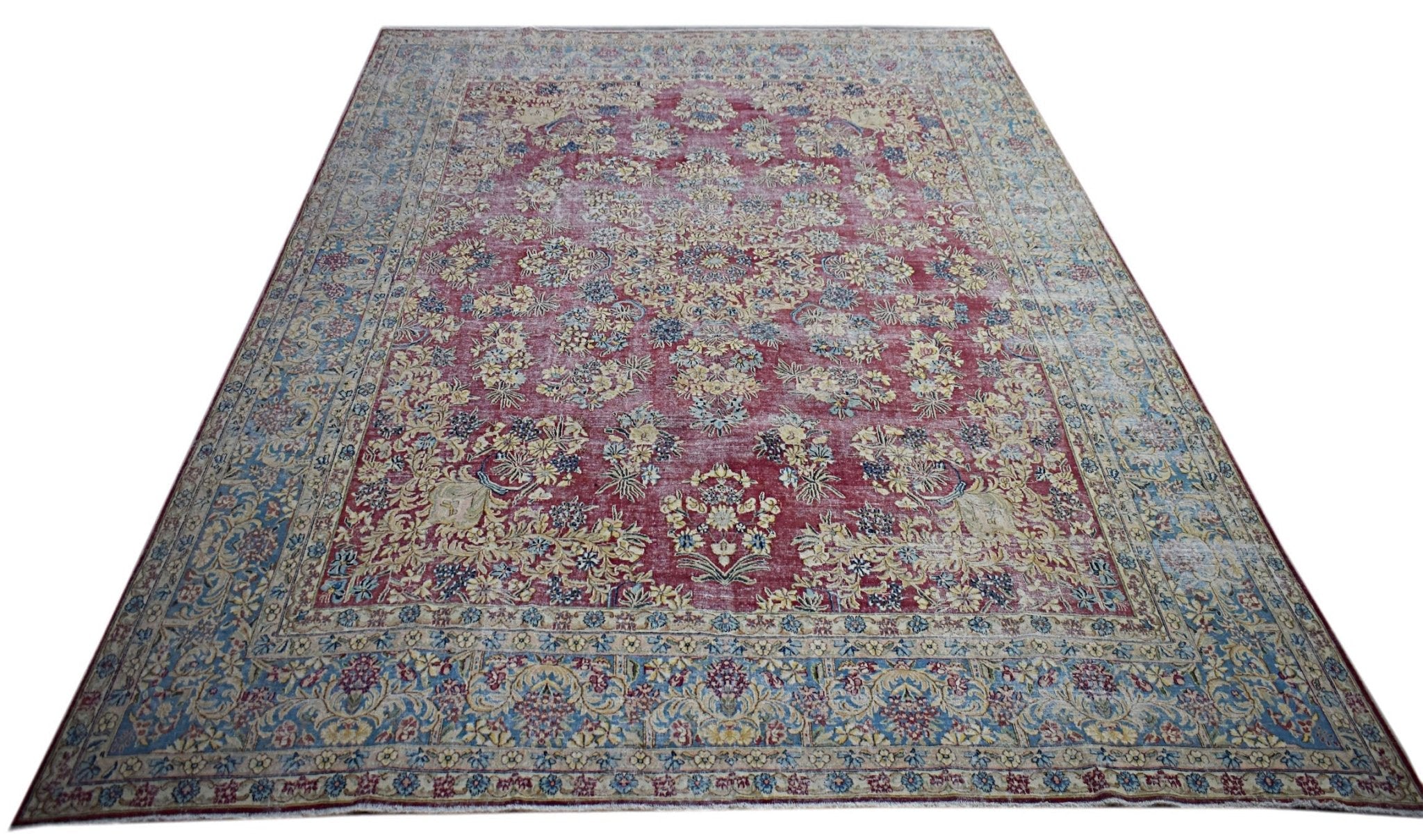 A vintage Persian Kerman rug featuring an intricate floral medallion design in red and blue tones.
