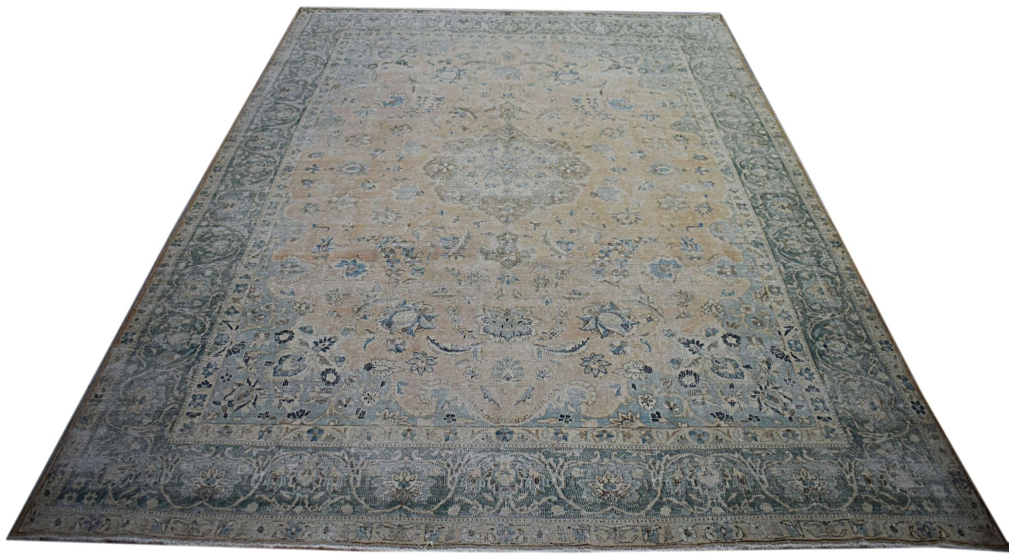 A vintage Persian Kerman rug featuring a central medallion and intricate floral patterns in blue.