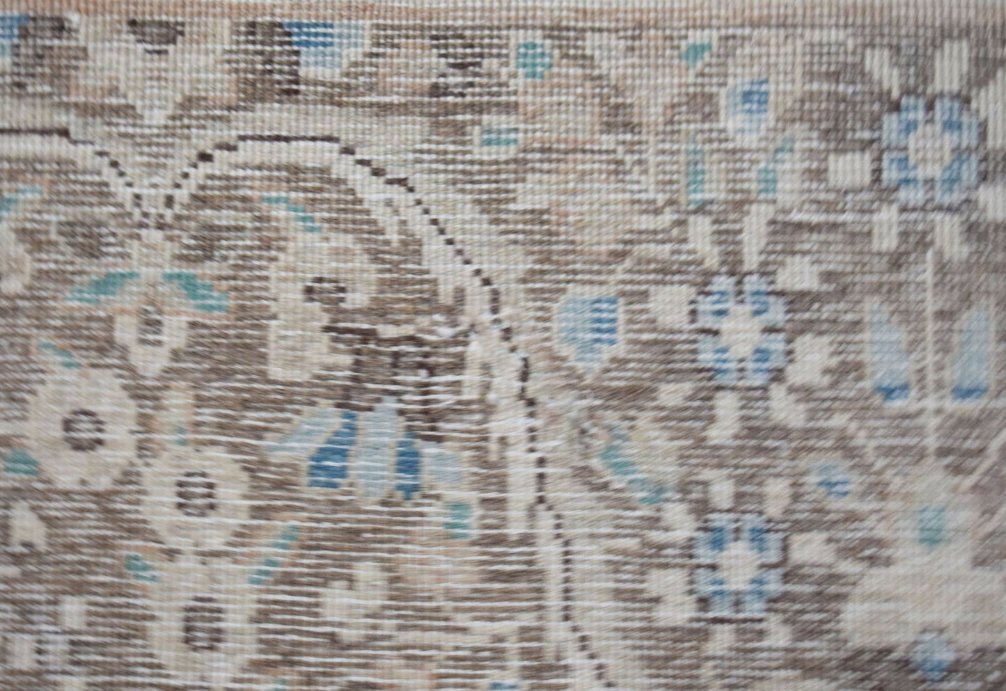 A close-up of a vintage Persian Kerman rug featuring intricate floral patterns in muted tones.