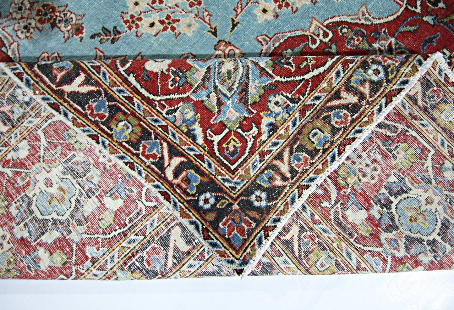A vintage Persian Kerman rug featuring an intricate floral medallion design in red and blue tones.