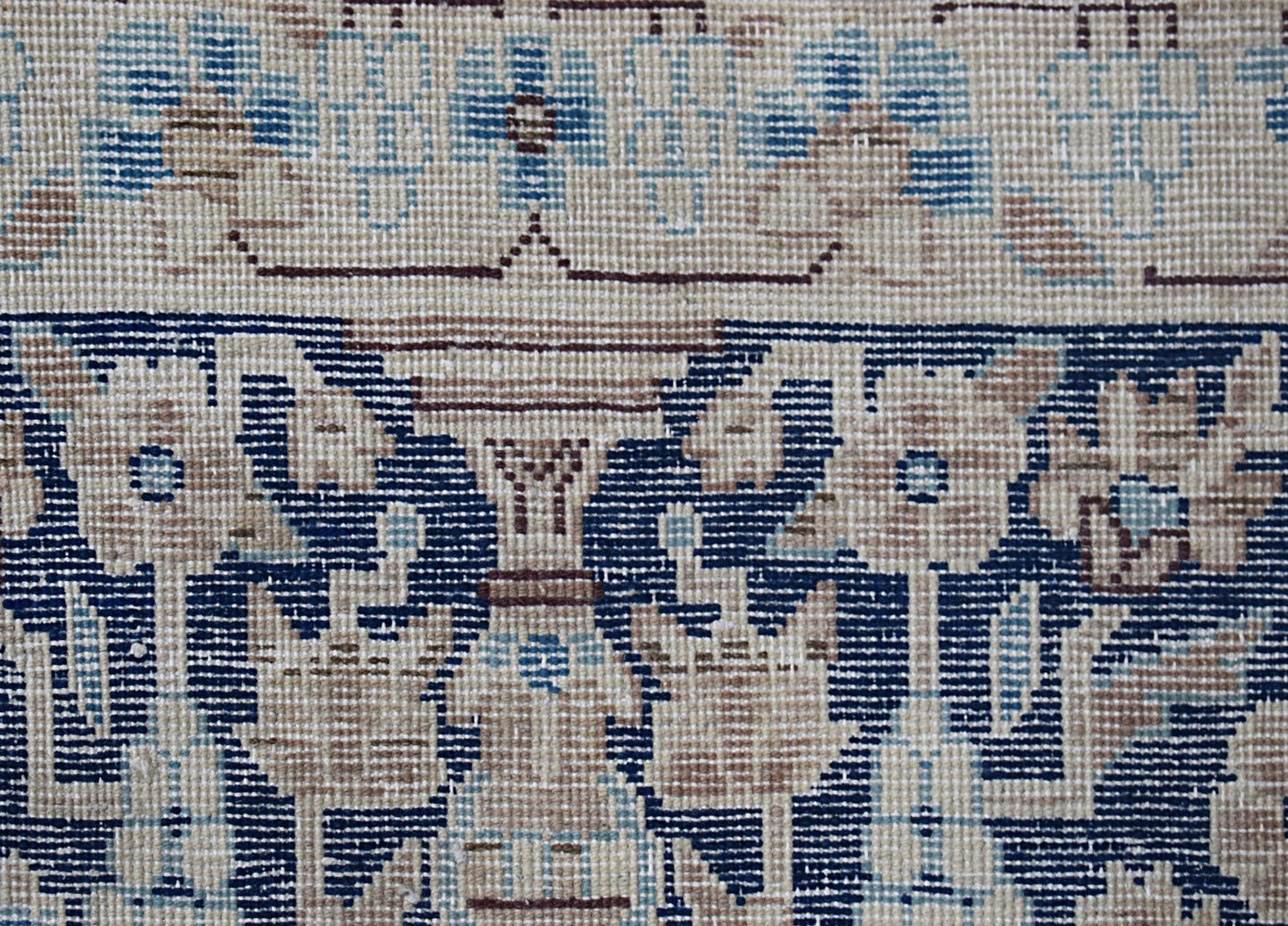 A close-up of a vintage Persian Kerman rug featuring intricate floral patterns in blue and beige.