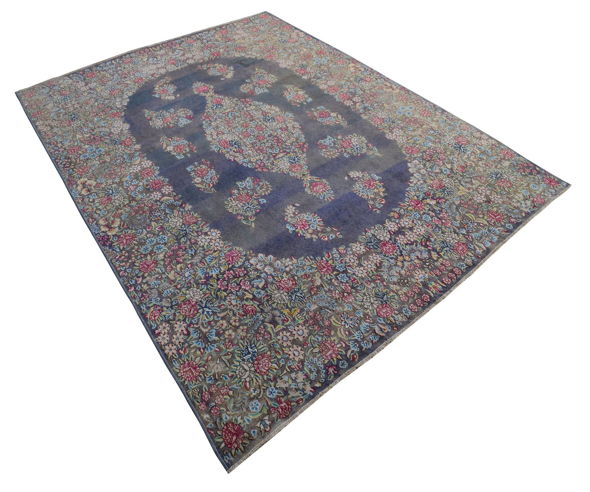 A vintage Persian Kerman rug featuring a central floral medallion on a blue field.