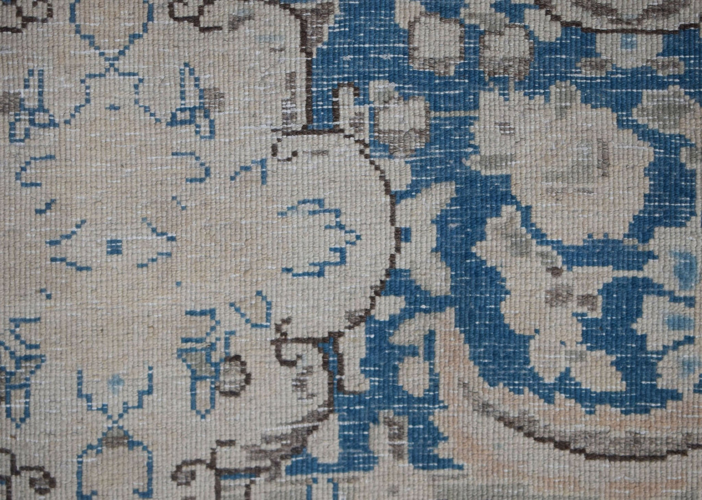A close-up of a vintage Persian Kerman rug featuring intricate blue and cream floral patterns.