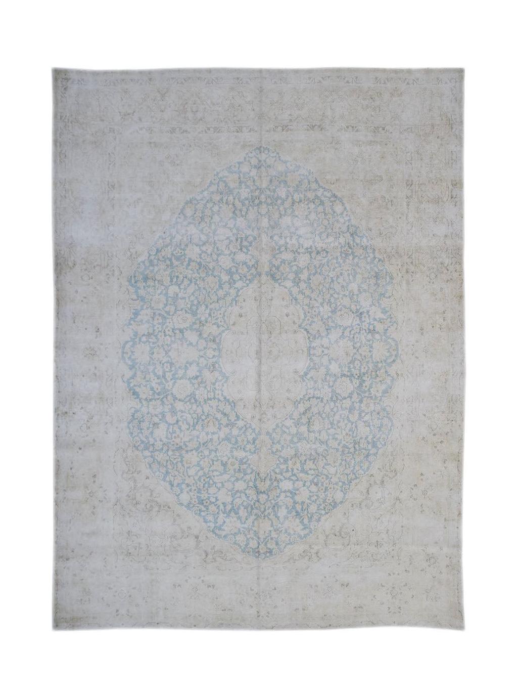 A vintage Persian Kerman rug featuring a central blue floral medallion on a light beige field.
