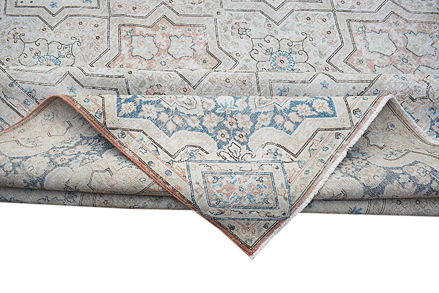 A vintage Persian Kerman rug featuring a geometric star pattern in soft blue and peach tones.
