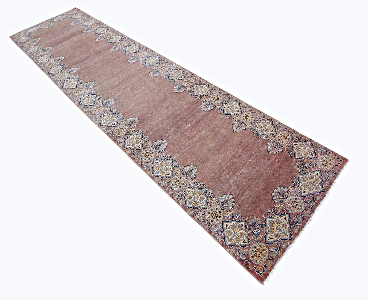 Vintage Persian Kerman runner featuring a dusty rose field with intricate floral borders and a soft, weathered pile.