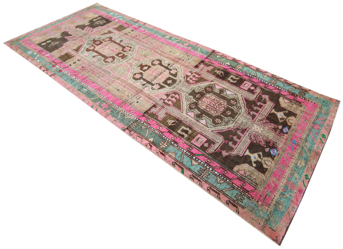 Vintage Persian Lori runner featuring geometric diamond medallions in pink, teal, and brown hand-spun wool.