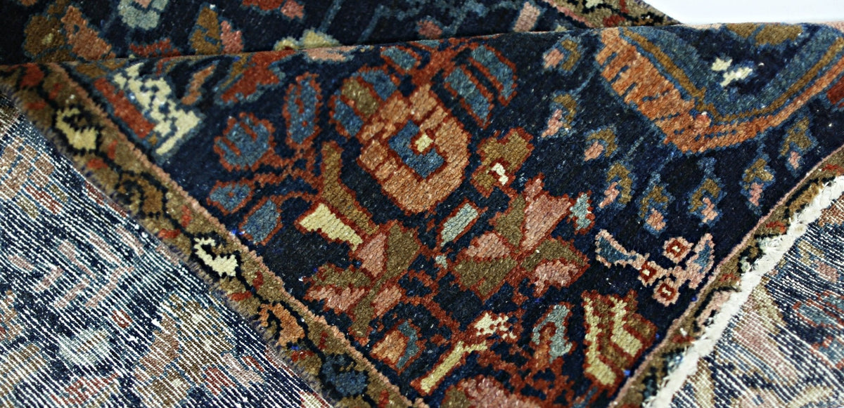 Close-up of a vintage Malayer runner showing intricate floral patterns in deep indigo, rust red, and sage wool.