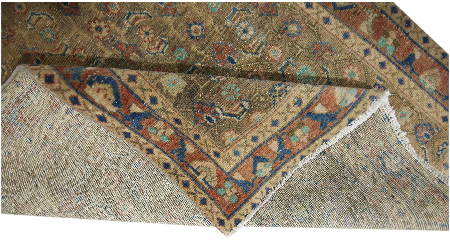 A vintage Persian Hamadan runner with a folded corner showing its wool pile and cotton foundation.
