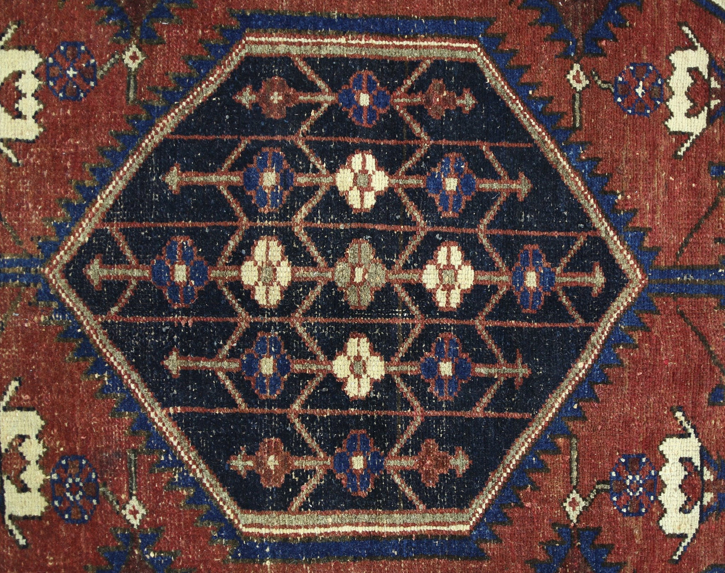 A vintage Persian Mazlaghan rug featuring a central dark blue hexagon with geometric floral motifs.