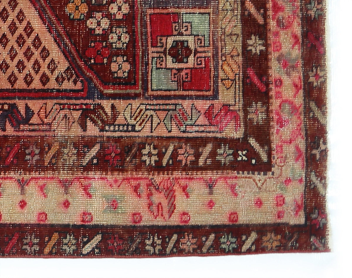 Close-up of a vintage Persian Meshkin rug featuring geometric patterns in madder red, indigo blue, and earthy wool tones.