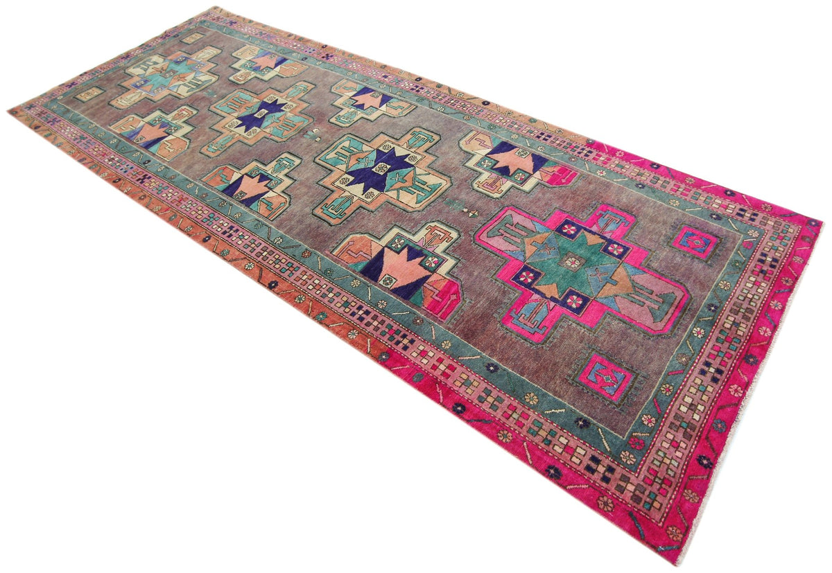 Vintage Meshkin runner featuring angular medallions in pink, blue, and teal on a weathered grey field with geometric borders.