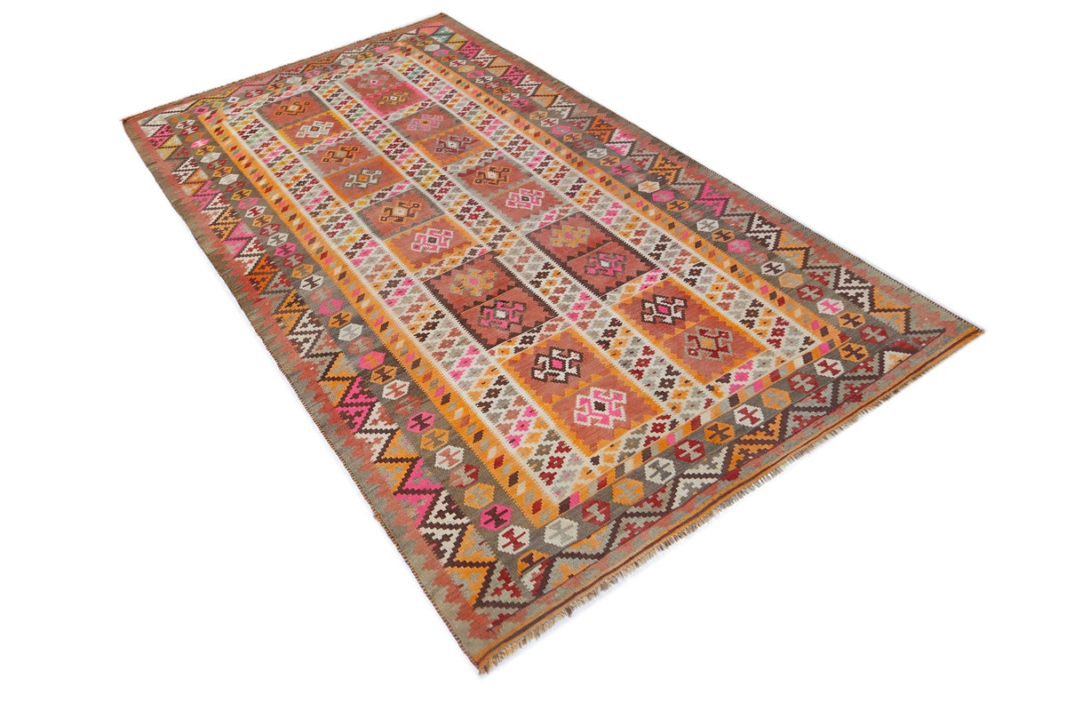 Handwoven vintage Persian Qashqai kilim featuring geometric patterns in warm earth tones, pinks, and orange wool.