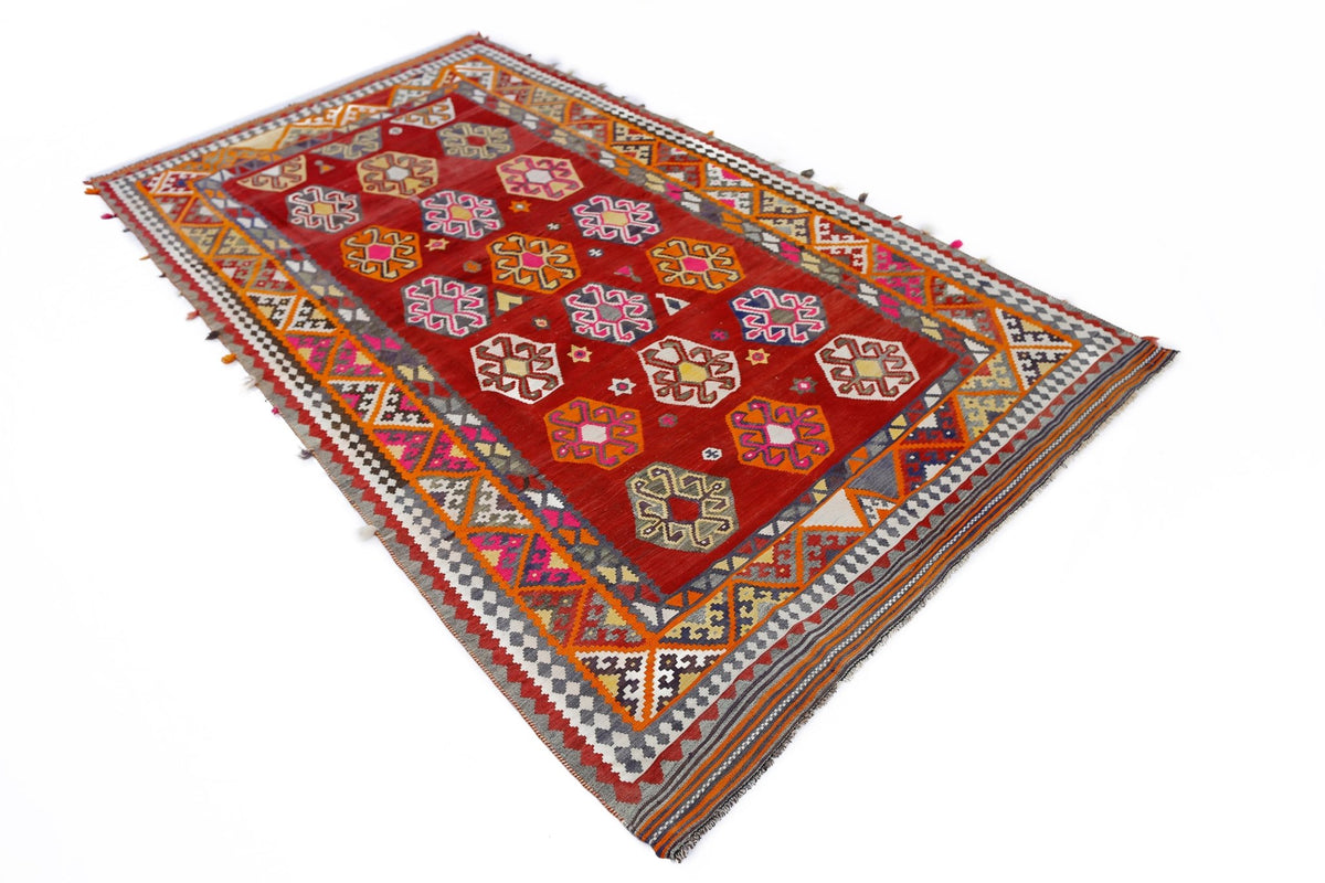 Handwoven red Persian Qashqai kilim with geometric tribal motifs, colourful wool patterns, and a fringed border.