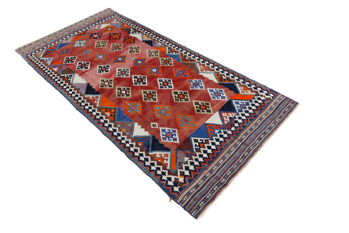 Vintage Persian Qashqai kilim runner featuring a red field with geometric diamond patterns, colourful tribal motifs, and fringe.