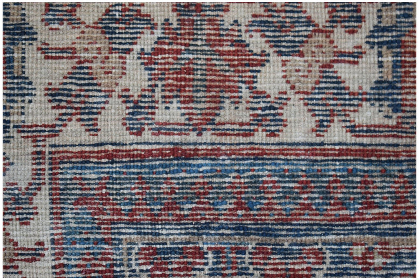 A close-up of a vintage Persian Ghashghai rug featuring intricate red and blue geometric patterns.