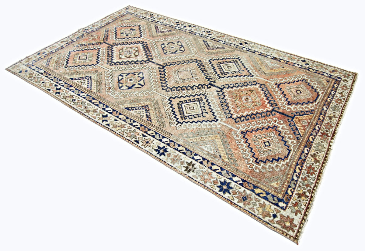 Vintage Persian Qashqai rug featuring a geometric diamond pattern in muted terracotta, blue, and cream hand-spun wool.