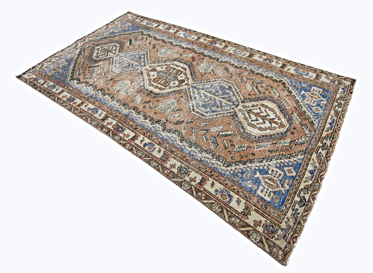 Vintage Persian Qashqai rug with geometric blue and terracotta patterns, hand-knotted wool on a cotton foundation.