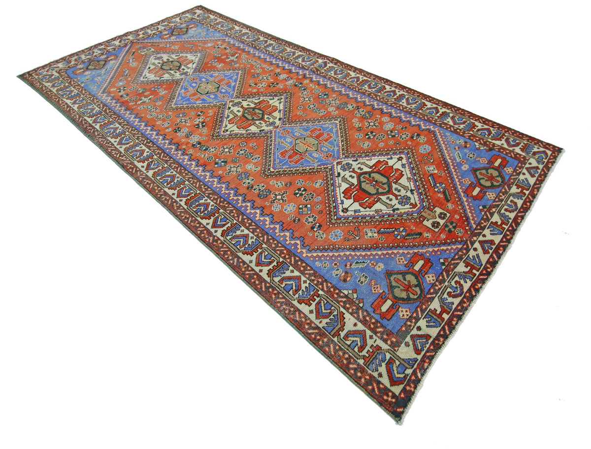 A vintage Persian Ghashghai rug featuring a geometric diamond pattern in red and blue tones.