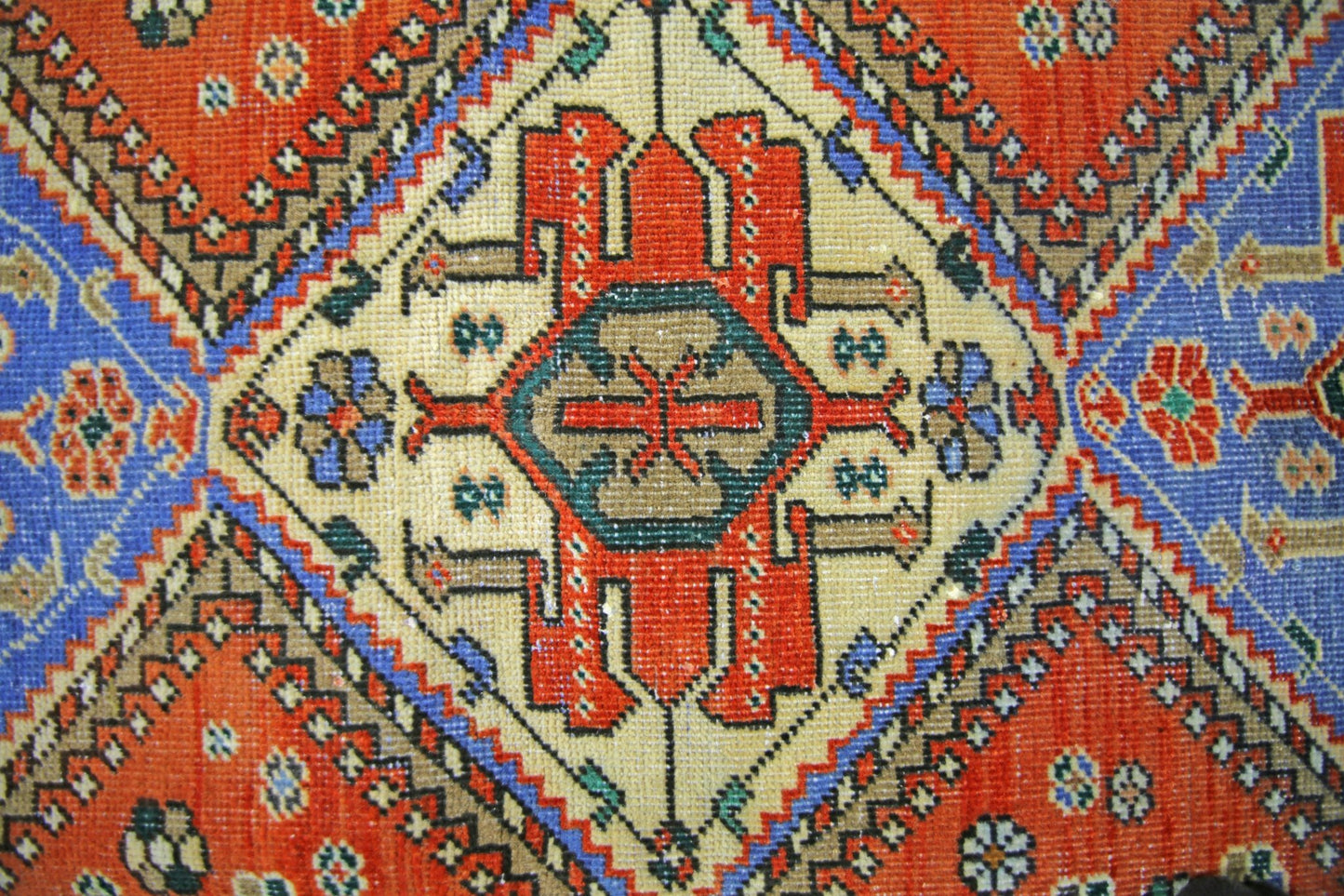 A vintage Persian Ghashghai rug featuring a central geometric medallion in red, blue, and tan.
