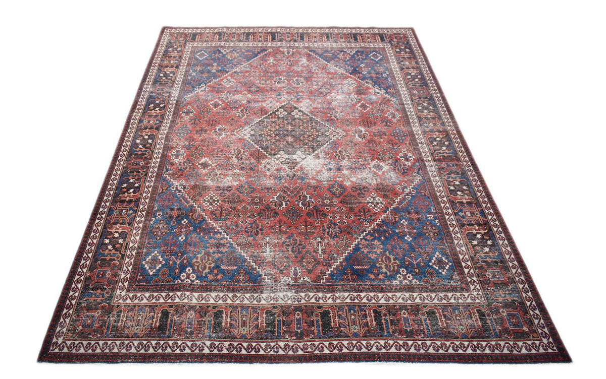 A vintage handwoven Persian Ghashghai rug featuring a distressed red and blue geometric pattern.