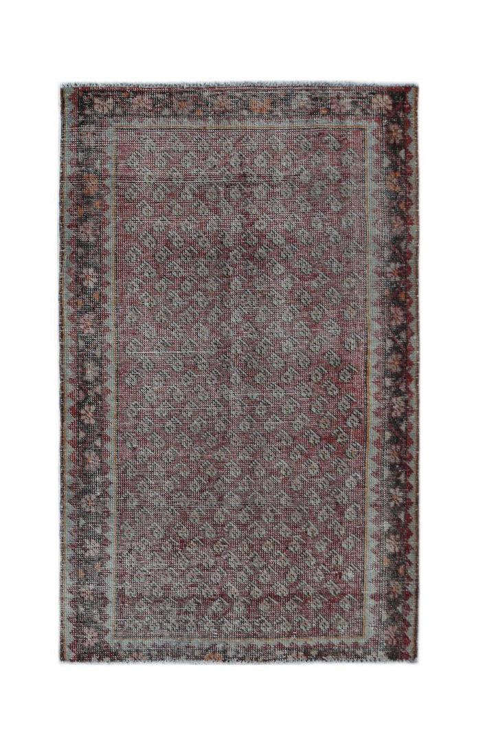 A vintage handwoven Persian rug featuring a faded red and grey geometric pattern.