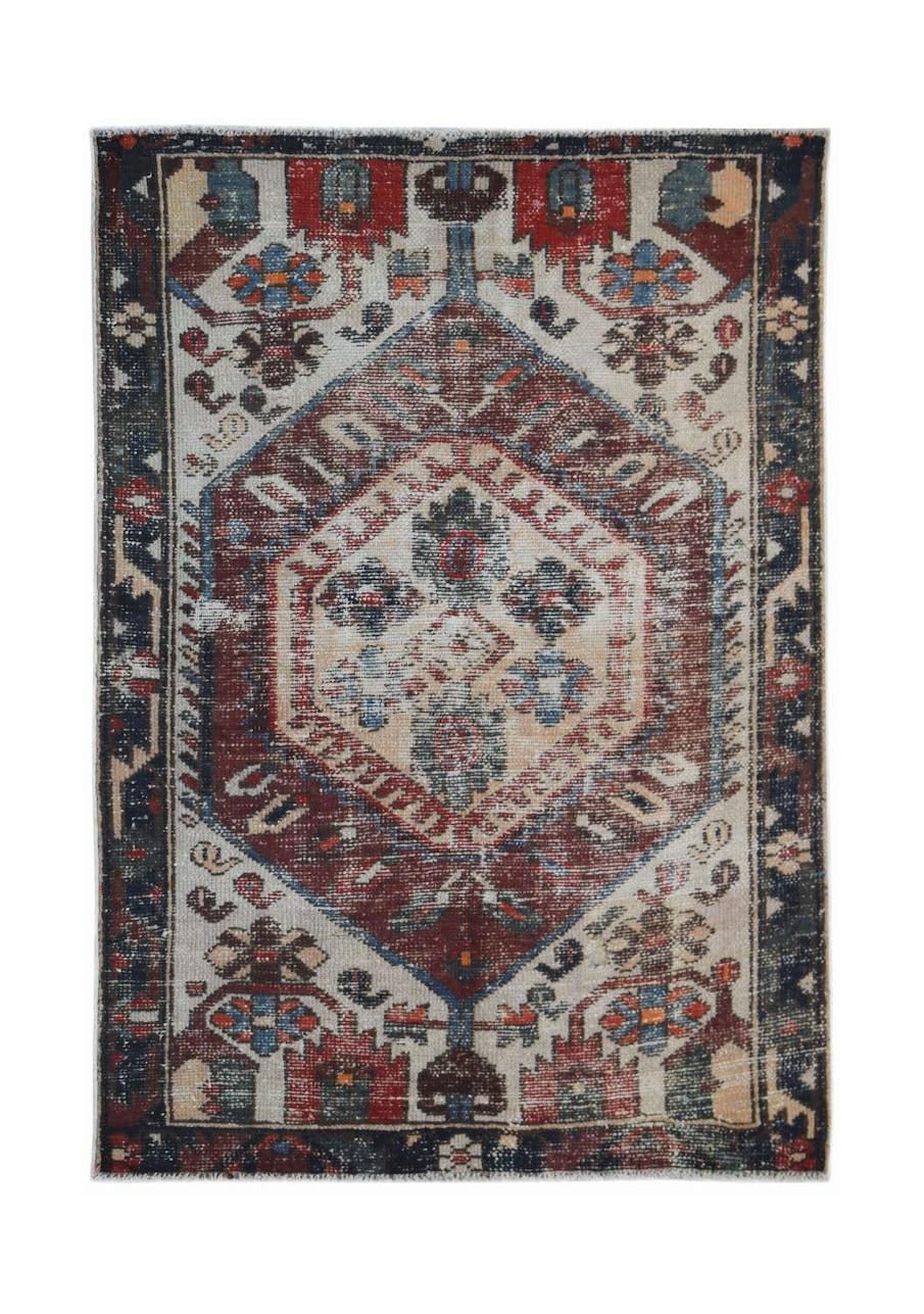 A rectangular vintage Persian rug featuring a central geometric medallion in red, blue, and cream.