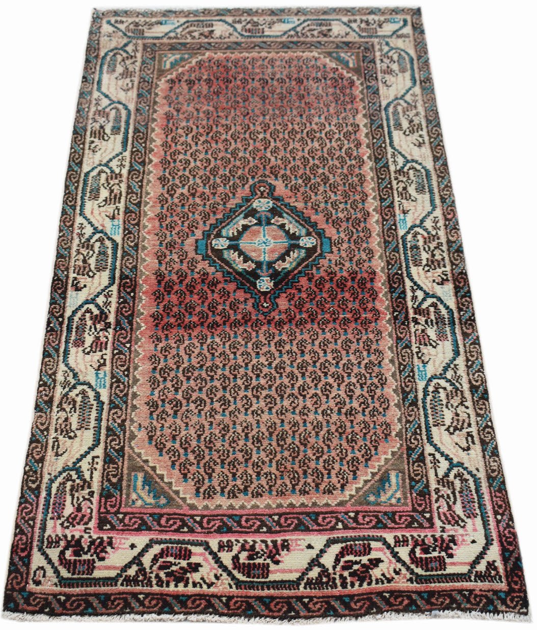 A vintage handwoven Persian rug featuring a pink field with a central diamond motif and patterned borders.